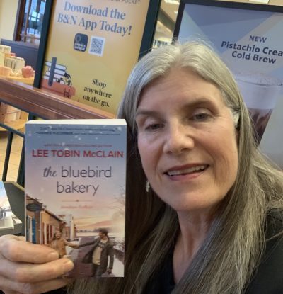 Lee Tobin McClain holding a copy of her new book, The Bluebird Bakery