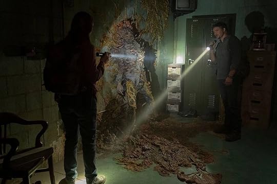 Anna Torv and Pedro Pascal use flashlights to see the dead infected body on a wall on The Last of Us