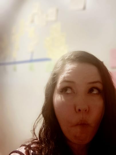 The Author standing in front of a wall. Index cards are tapped to the wall with scene ideas for her books.