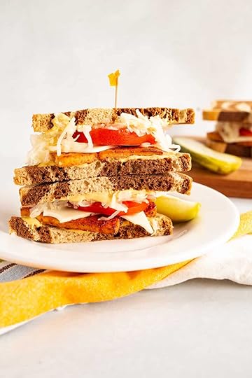 tofu pastrami sandwich with kraut, tomato, cheese, and mustard on rye