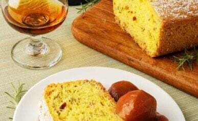 A slice of olive oil rosemary cake with some preserved fruit and sherry.