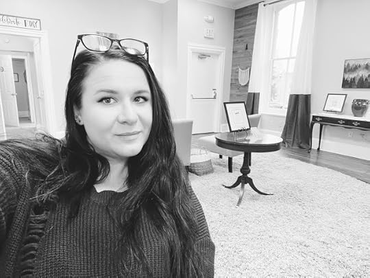 Black and white image of Amanda from the chest-up with the backdrop of a large studio room in her new practice