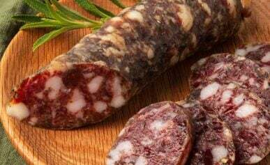 A link of venison salami sliced on a plate.