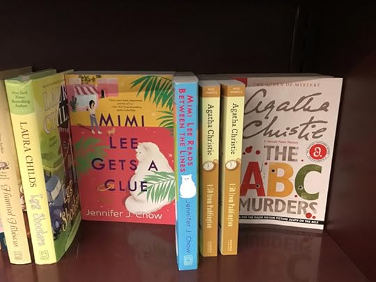 Jennifer J. Chow's books (Mimi Lee Gets A Clue & Mimi Lee Reads Between the Lines) on a bookshelf next to Agatha Christie's (4:50 From Paddington and The ABC Murders)