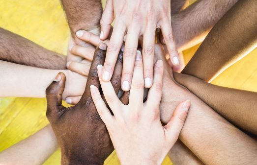 Top view of multiracial stacking hands - International friendship concept with multiethnic people representing peace and unity against racism - Multi racial love and integration between diversity