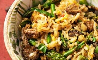 Close up of a bowl of mushroom fried rice with morels and asparagus.