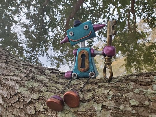 A blue robot sculpture sitting in a tree. The robot is holding a key and wearing a bowler hat, and has an antique keyhole embedded in its chest.