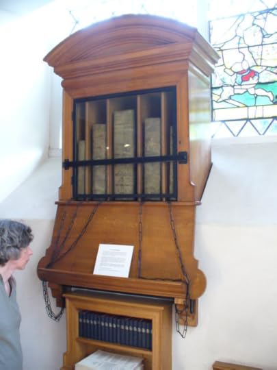 A wooden library cabinet contained a collection of books that are chained to the cabinet.