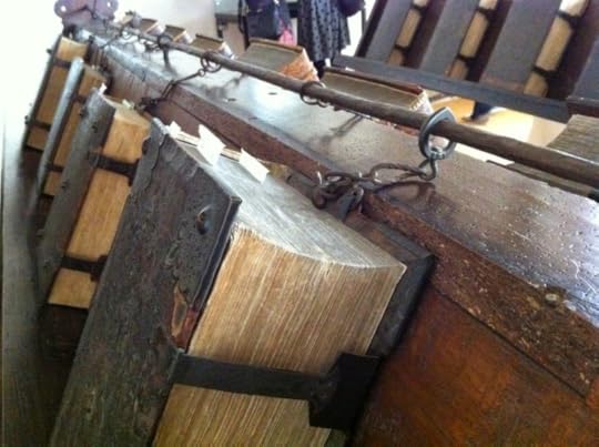 Ancient books on a wooden stand and chained to a metal rod.