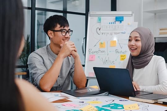 Team working around a table in an office. Smiling.
