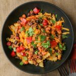 black bowl of Chili Cheese Fries with lots of toppings.