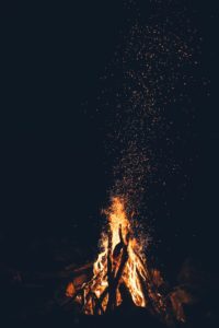 Blazing campfire at night throwing a scattering a sparks into the air like ideas floating from the flame of inspiration.
