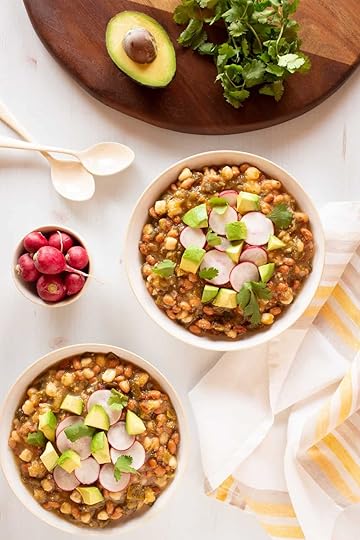 bowls of vegan tomatillo stew with beans, hominy, radishes, and avocado