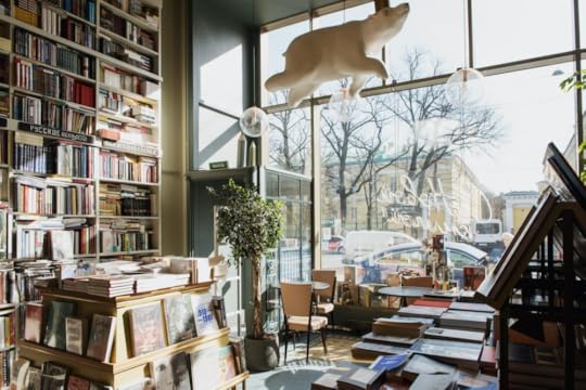 The interior of a bookstore with large plate glass windows facing onto a city street.