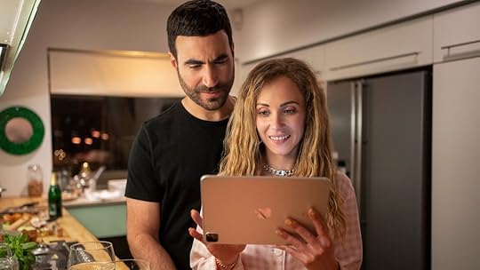 Roy stands behind Keeley looking over her shoulder to her iPad on Ted Lasso