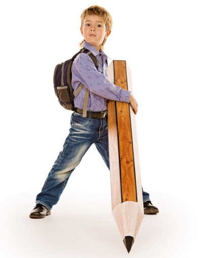 Photo of a boy student wearing a backpack holding a giant wooden pencil that is taller than he is. Understanding dysgraphia means understanding that it can be difficult and even painful to hold a pencil in order to write legibly.