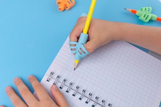 Photo of a child writing in a notebook using a pencil equipped with a pencil grip that helps them hold the pencil properly. Understanding dysgraphia and how it affects a student is important.