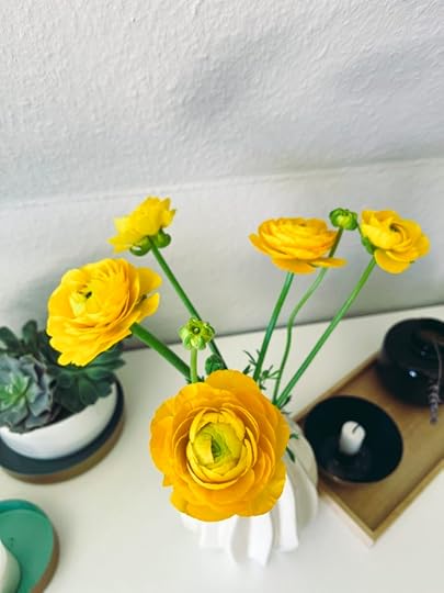 Leuchtend gelbe Ranunkeln in einer Vase vor Raufaser.