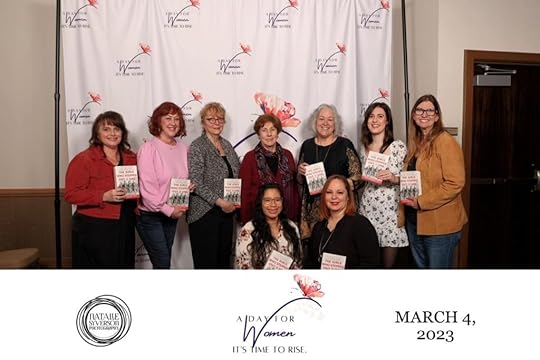 Multiple women, including Mari K. Eder, posing in front of a banner reading 
