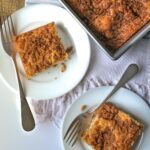 plates on table with squares of cinnamon coffee cake, next to baking pan on towel.