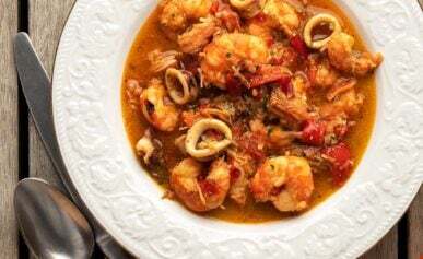 A bowl of zarzuela de mariscos with shrimp, crab and squid.