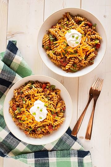 bowls of taco pasta topped with cheese and sour cream