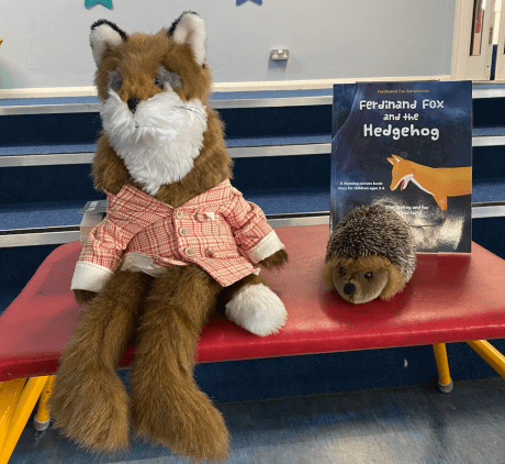 Fox and hedgehog soft animal toys sitting on a table in front of the picture book Ferdinand Fox and the Hedgehog