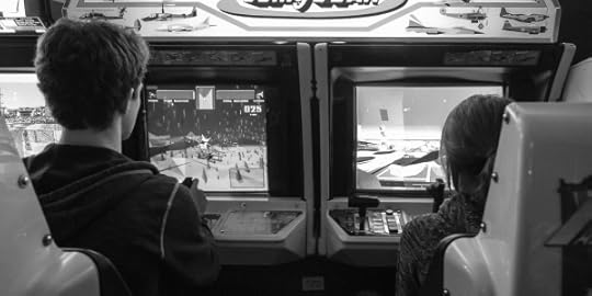 Two children seated at arcade games