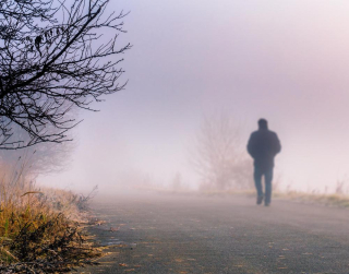 Man-walking-along-foggy-road