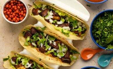 three ribeye tacos in a taco holder, with chiltepin chiles and other accompaniments.