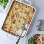 tray of scalloped potatoes on the dinner table with other platters of food.