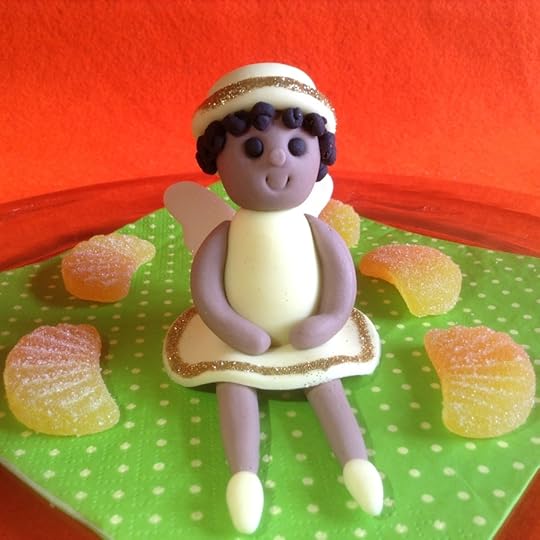 Dark skinned fairy in a pale yellow dress, hat and shoes.