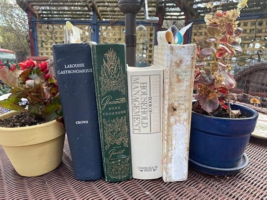 cookbooks set up between pots of geraniums
