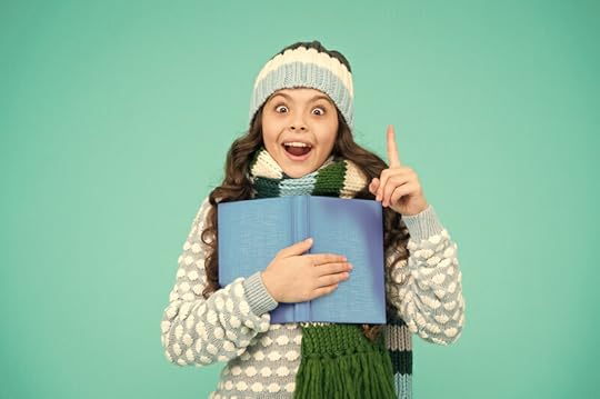 Photo of a girl wearing winter clothes against a solid green background. She holds an open book to her chest with one hand and holds the index finger of her other hand up in the air. Her face looks a little maniacally inspired, but happy too. If your dyslexic learner has been feeling defeated, maybe they need a dyslexia inspiration intervention.