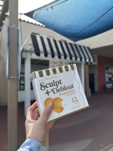 Cassey Ho holding the new snickerdoodle Blogilates protein bars in front of bakery