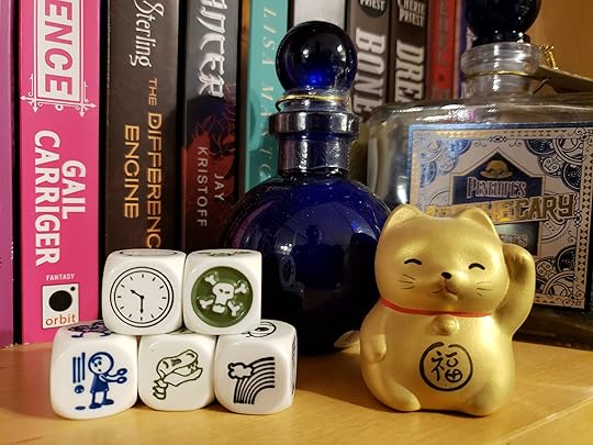 Five of Rory's Story Cubes displaying pictures of a clock, a skull and crossbones, an object falling beside a person, a dinosaur skeleton, and a rainbow.