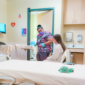 photo of Penny sitting near a hospital bed while a technician talks with her