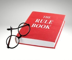 red book titles The Rule Book with a pair of black glasses