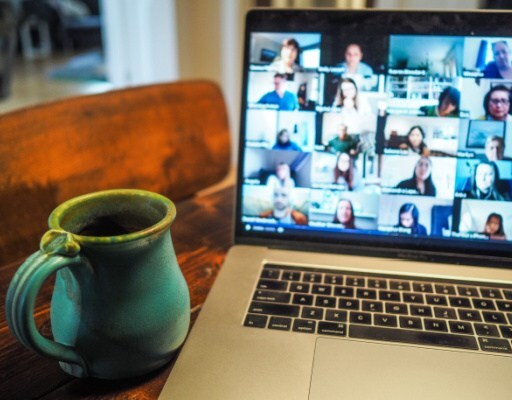 Zoom screen with adult faces on a laptop, large ceramic mug nearby
