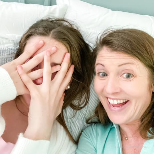 Marilee and Amy Julia take a selfie with Marilee peeking through her fingers and Amy Julia smiling widely at the camera