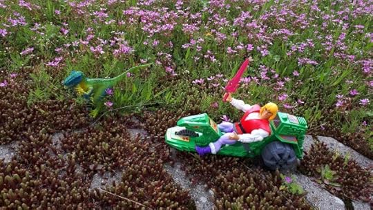Adam is riding the Road Ripper, while a Raptor appears in the grass.