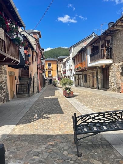 A clean stone street with bright yellow, grey, and reddish houses around it