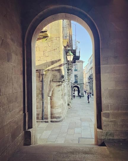 A narrow, perfectly rounded archway; beyond it, more archways, and a stone paved street with figures in the distance