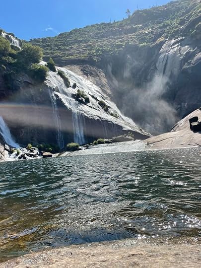 Water streams down big granite rocks into a deep, dark blue pool with lapping waves