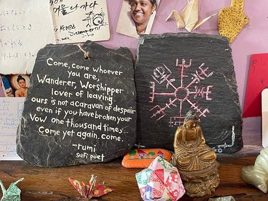 Two slate stone sit on a table with an assortment of things, on stone the Norwegian compass, the other with the words: