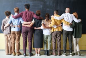 Group of teachers and students Standing Indoors facing a chalkboard