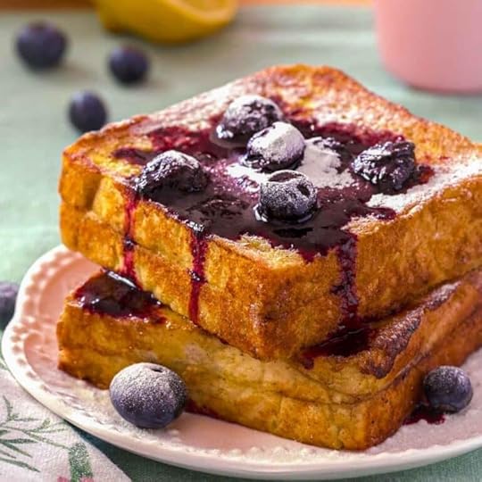 A close-up of lemon blueberry French toast. The stuffed French toast is topped with blueberry compote, and powdered sugar.