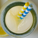 overhead shot of milk jar full of ginger lemonade with ice and straws.