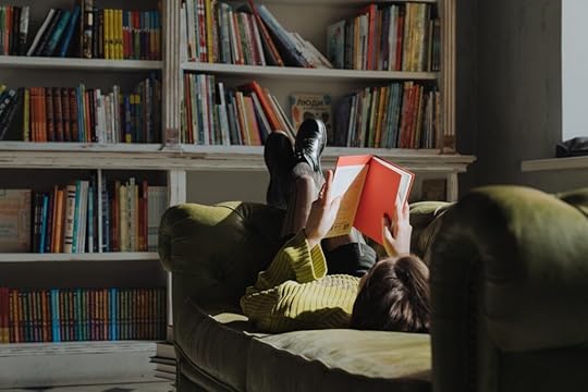 A girl reading a book on a couch.