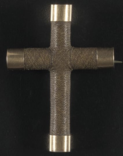 A small cross made from tightly woven hair with metal caps on the ends.